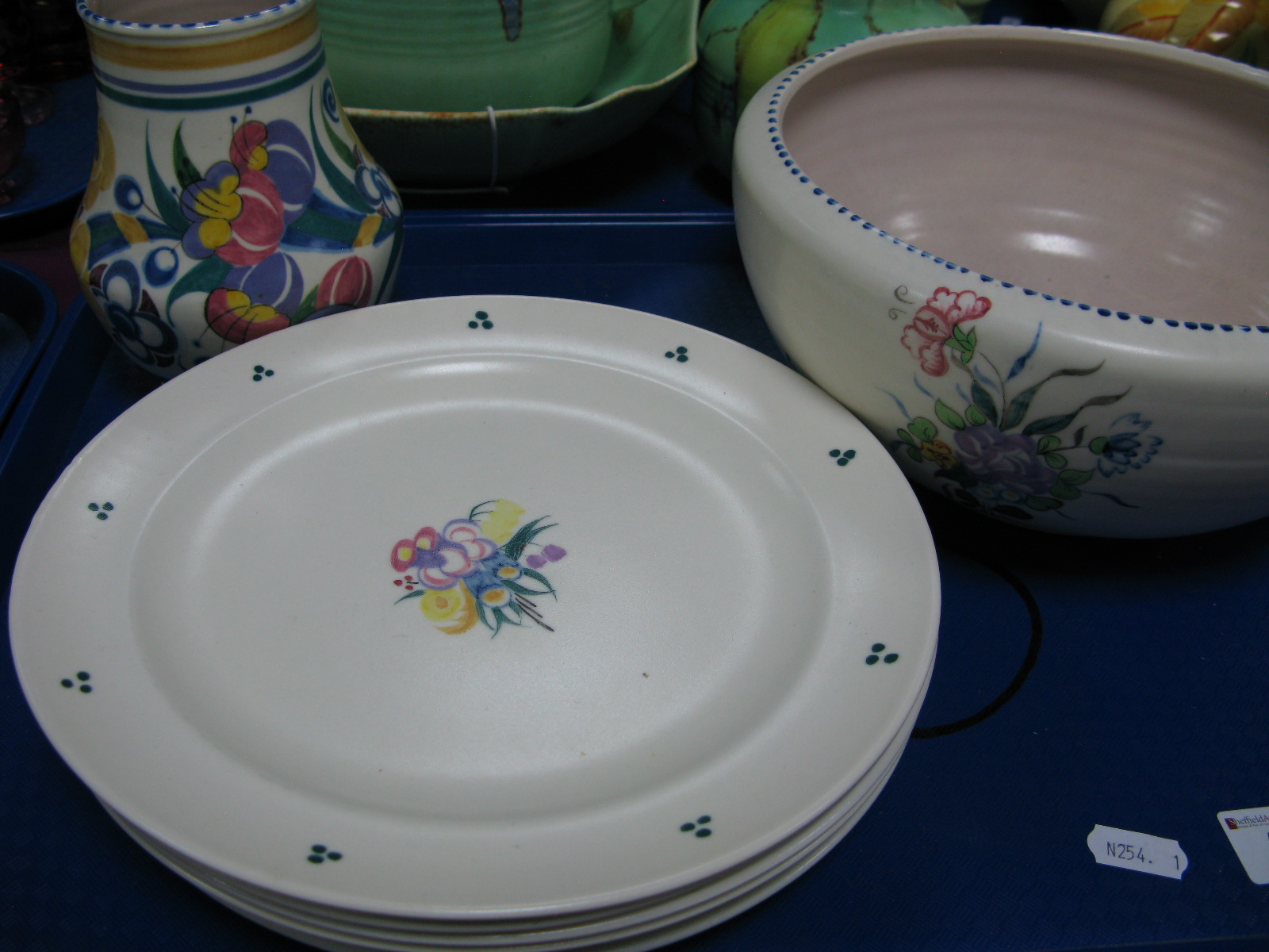 Six Poole Pottery Plates, each with stylized floral motif to centre, three green dot bunches to