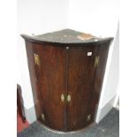 An Early XIX Century Oak Bow Fronted Corner Cupboard, with internal shelves, hinges