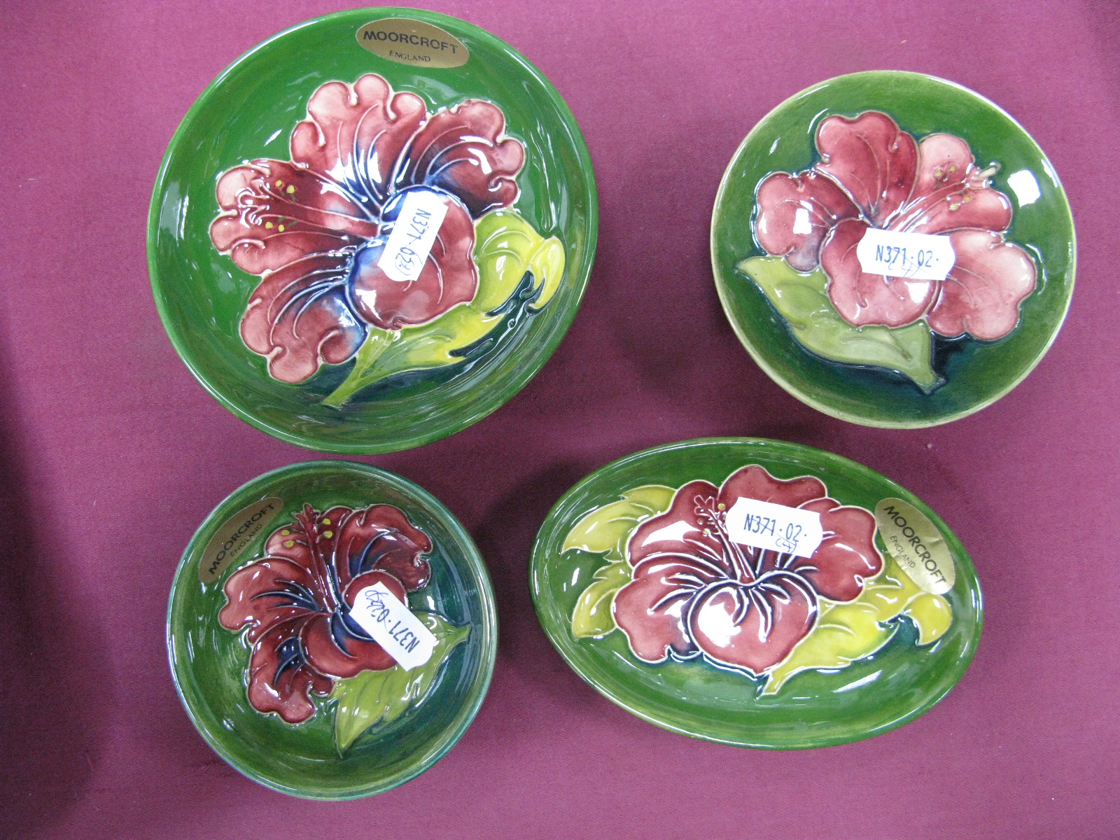 A Moorcroft Pottery Shallow Circular Dish, painted in the 'Hibiscus' pattern against a green ground,
