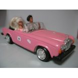 A Barbie Pink Rolls Royce, silver wheels, with Barbie and Ken figures.