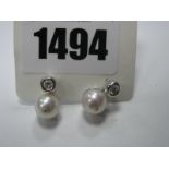 A Pair of Modern Pearl and Diamond Set Earrings, each single pearl bead below rubover set