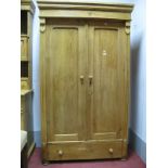 A Pine Wardrobe, with a stepped cornice, twin panelled cupboard doors, long drawer on turned bun