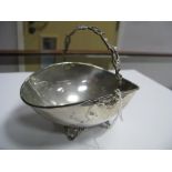 A Basket Dish, of plain oval form with leaf scroll overhead handle, raised on four openwork feet,