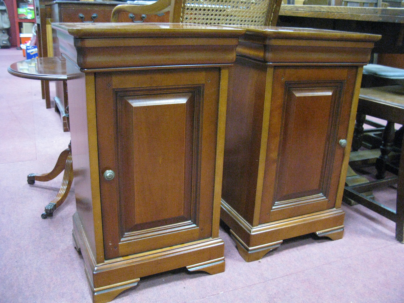 A Pair of Bedside Cupboards, with panelled doors, on bracket feet.
