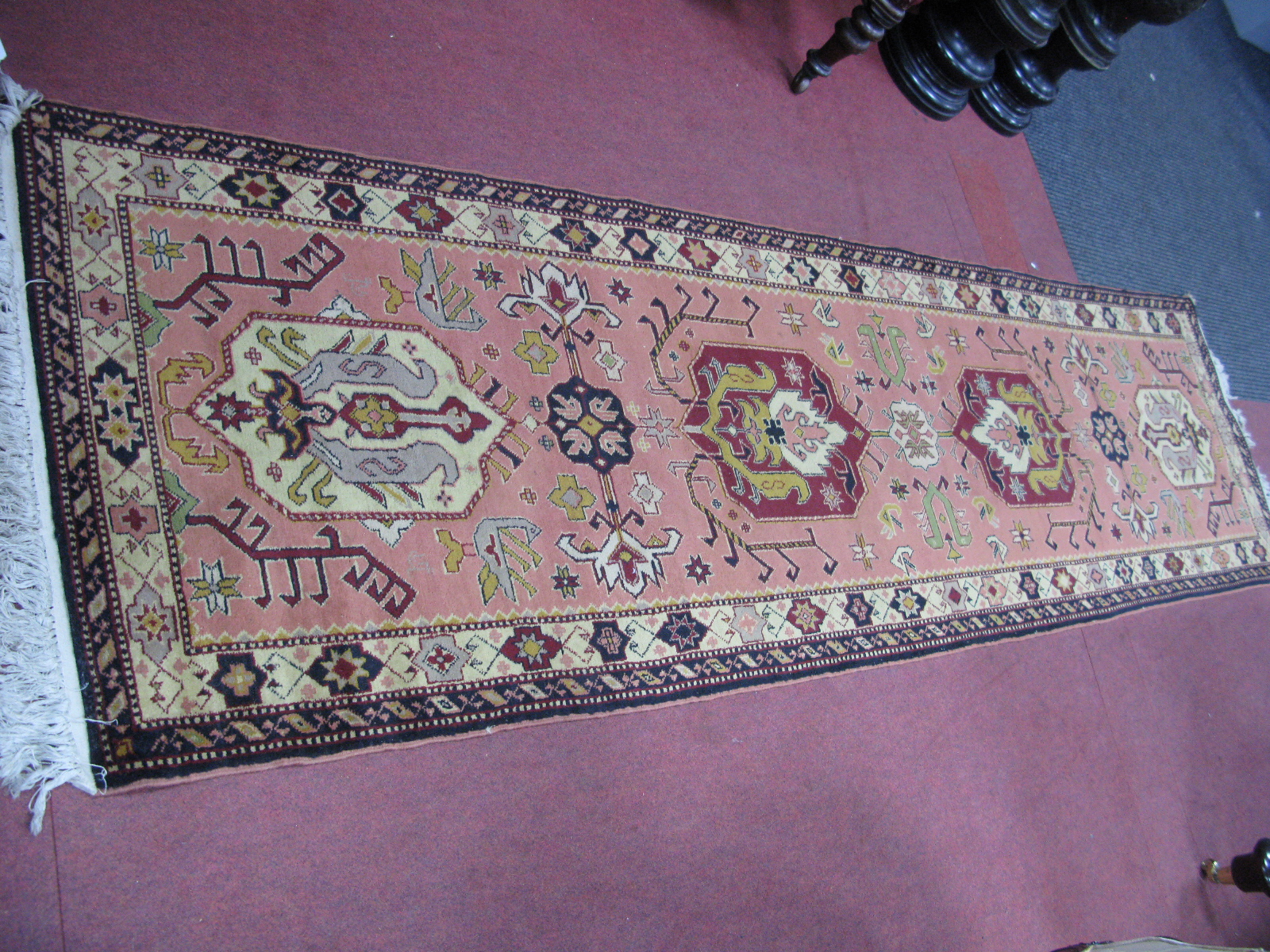 A Tassled Wool Runner, circa mid XX Century with four larger and three smaller centre motifs, all
