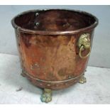 A Victorian riveted copper Firewood Bin, circular with brass lion's mask and ring handles, supported