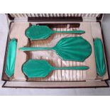 A cased early 20th century six-piece Dressing Table Set, engine turned silver backs with emerald