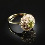 A 14K YELLOW GOLD, DIAMOND, AND PERIDOT LADY'S RING, centering an oval shaped prong set peridot