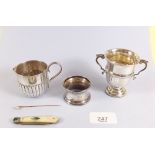 A small group of silver items including miniature trophy cup, cream jug, napkin ring, gold stick pin