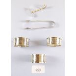 Three silver napkin rings, a pair of tongs and a pusher - 70g