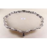 A large silver plated pie crust edge salver on four scroll feet