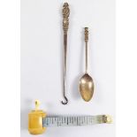 A silver button hook, a silver teaspoon and a bone cased needlework tape measure