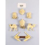 Four Japanese Meiji period miniature ivory masks, two miniature carved camels and a manicure tool