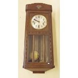 A oak cased wall clock with glazed door and Westminster Chime