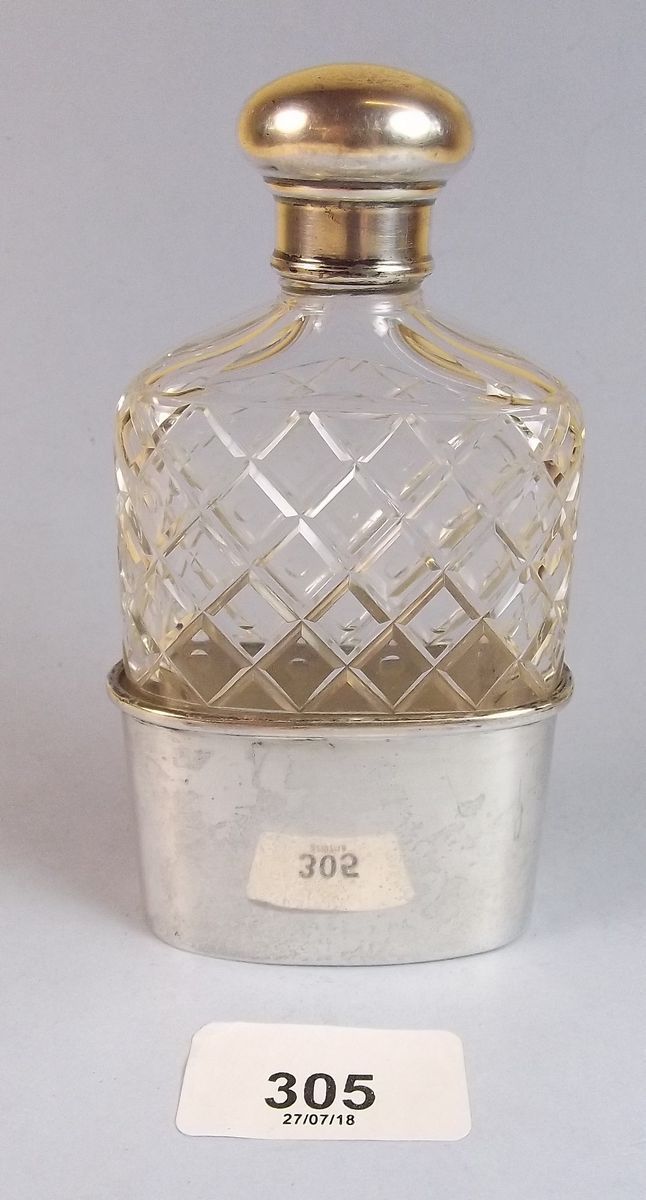 A cut glass silver topped spirit flask with silver plated cup base