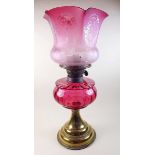 A Victorian oil lamp with cranberry glass etched shade and reservoir