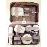 A travelling dressing table set with embroidered decoration in leather zip case