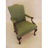 A green upholstered Georgian style armchair with carved arm supports and cabriole feet