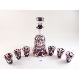 A Venetian purple glass liqueur decanter and six tot glasses with silver painted floral and