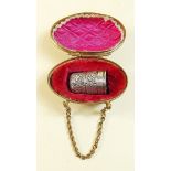 A silver thimble in gilt metal egg shaped case