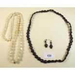 A carved jet necklace and earrings, and a white stone bead necklace