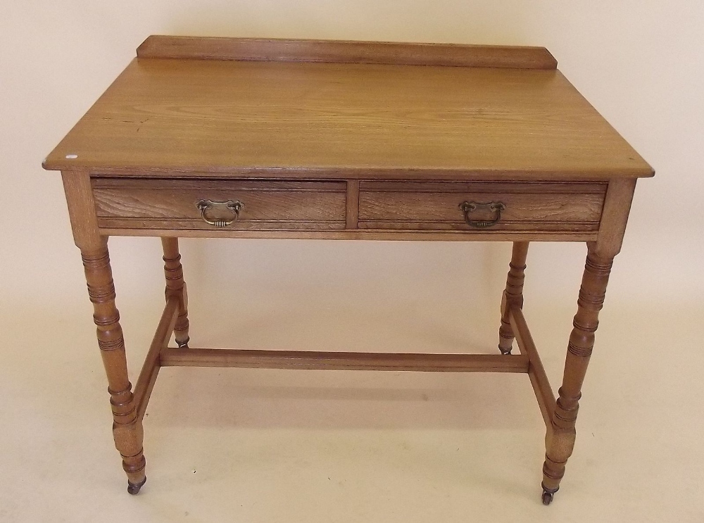 An Edwardian light oak side table with two frieze drawers on turned supports by Wilkinson and Son,