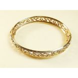 A 9 carat gold bangle with scrollwork decoration - 9g