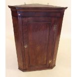 A Georgian oak corner cabinet with brass butterfly hinges and inlaid paterae