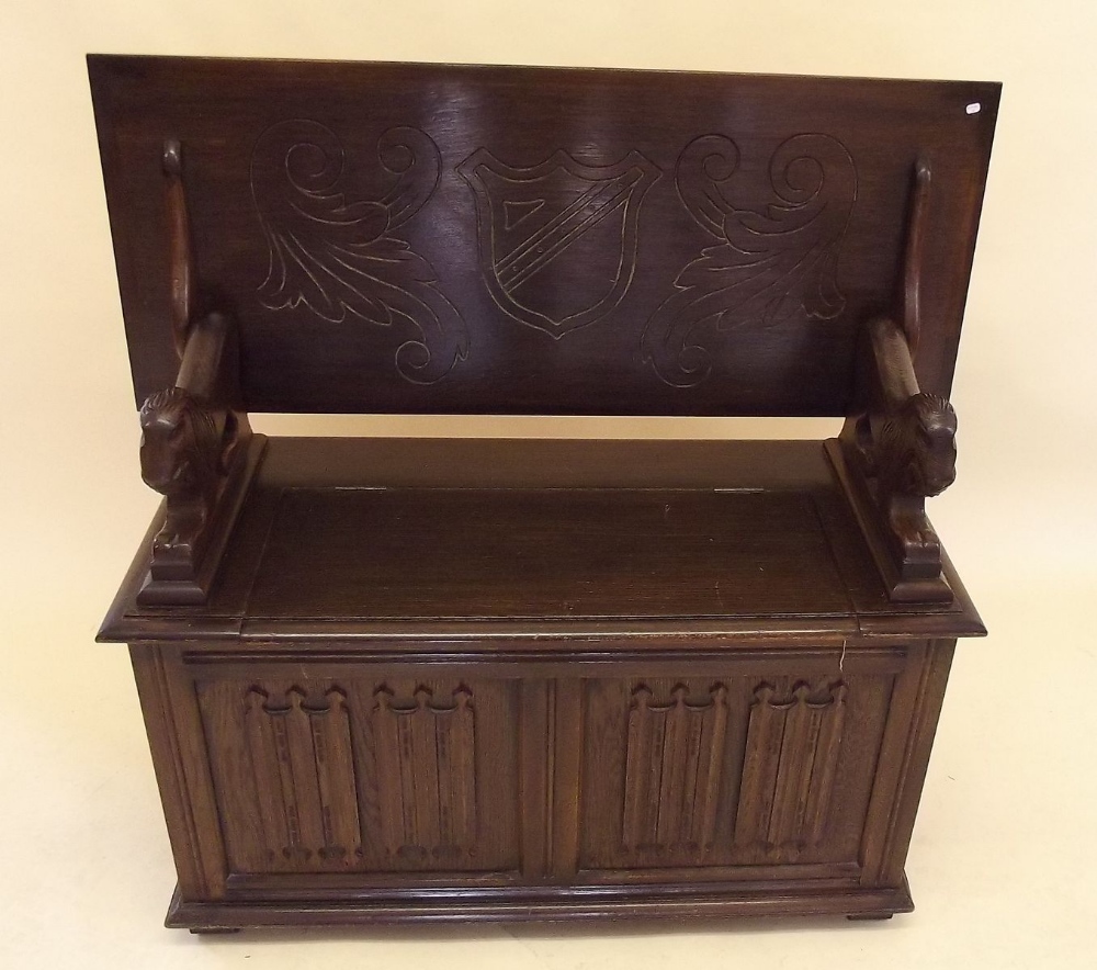 An oak monks bench with incised decoration and lion form arm supports