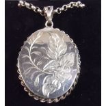 A silver oval engraved locket and chain - 26g in total