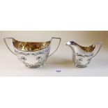 An Art Nouveau silver sugar bowl and milk jug embossed stylised poppies by James Deakin and Son -
