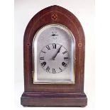 An Edwardian inlaid mahogany arched top Westminster chimes mantel clock