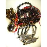 A group of large necklaces including a multi strand brown bead one with amber pendant, a purple