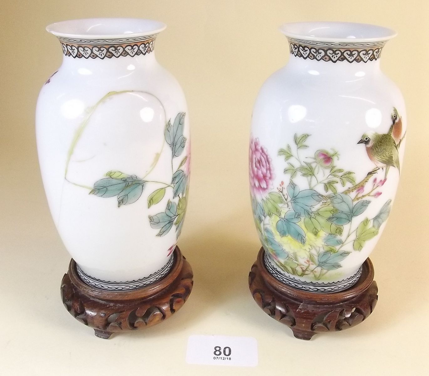 A pair of Chinese famille rose vases on wooden stands - one repaired and chips to rims