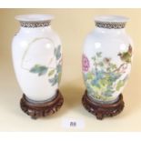 A pair of Chinese famille rose vases on wooden stands - one repaired and chips to rims