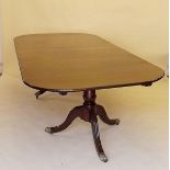 A good early 20th century mahogany twin pedestal dining table with large interleaf on brass paw feet