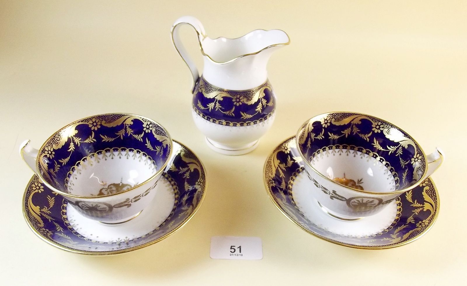 A pair of Minton cobalt and gold cups and saucers and similar jug c.1895