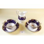 A pair of Minton cobalt and gold cups and saucers and similar jug c.1895