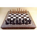 An early 20th century chess set with inlaid decoration and folding board