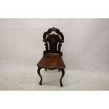 A Victorian mahogany hall chair, having carved back splat, solid seat, cabriole supports