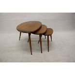 A nest of three Ercol pebble occasional tables, having elliptical tops over tapering splayed legs (