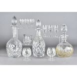 A collection of cut glass items, including three decanters and stoppers, a glass jug, and drinking