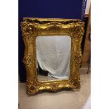 An ornate gilt framed bevel glass wall mirror, 122 cm x 101 cm max