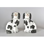 A pair of Staffordshire spaniels, black and white with yellow eyes, gold collars and chains, 25.5 cm