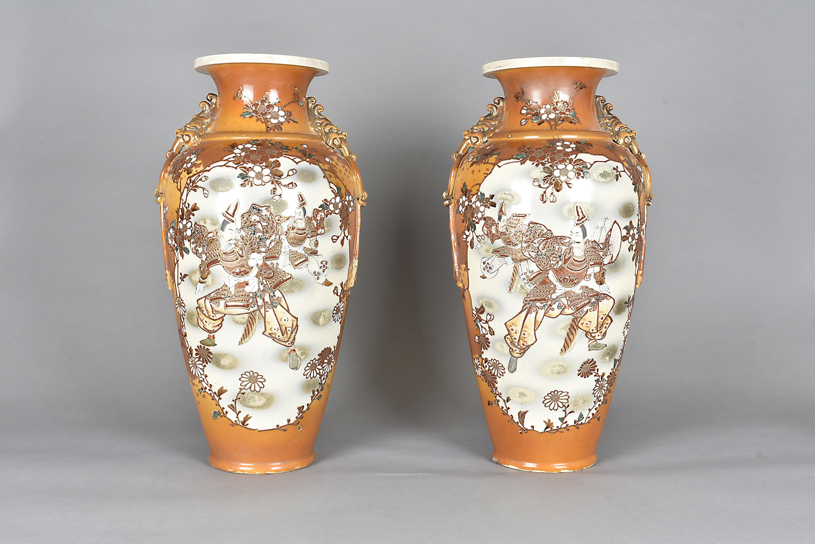 A pair of Japanese Meiji period satsuma vases, decorated with fighting warriors, moulded dragon mask