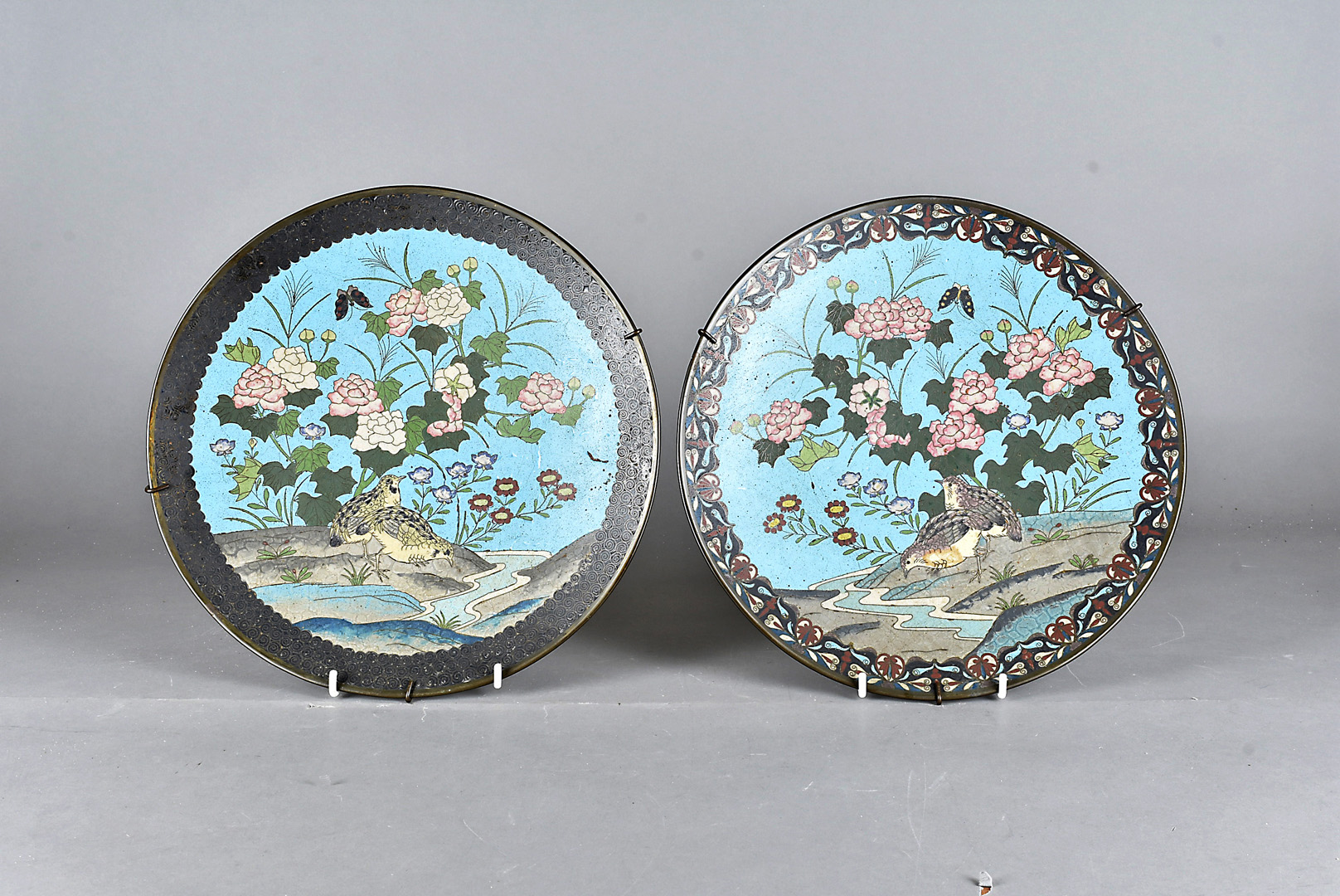 A pair of Chinese cloisonné wall chargers, both having bird and butterfly amongst foliate