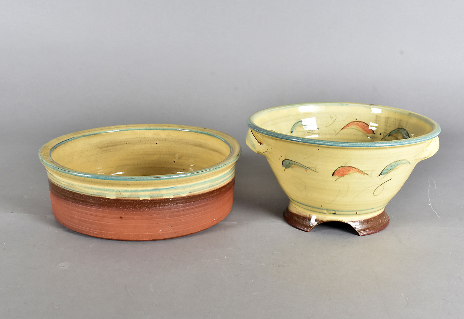 A Fannie Leach terracotta glazed salad bowl, and drainer, the ochre glaze decorated with a fish