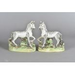 A pair of Staffordshire pottery Zebras, modelled standing on oval naturalistic bases, some