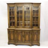 A reproduction oak elevated breakfront bookcase, the four panel glazed doors to shelved interior