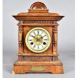 An Edwardian eight day mantle clock, the oak case with column design, flanking dial with black Roman